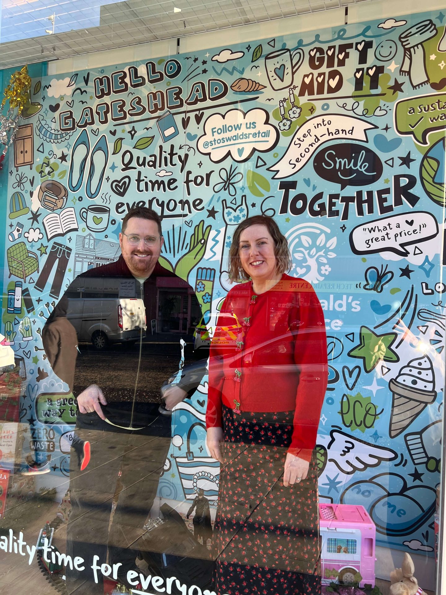 Anita Ball, Director of Income and Marketing at St Oswald’s Hospice standing and local illustrator James Dixon from Lines Behind who created the window mural featured